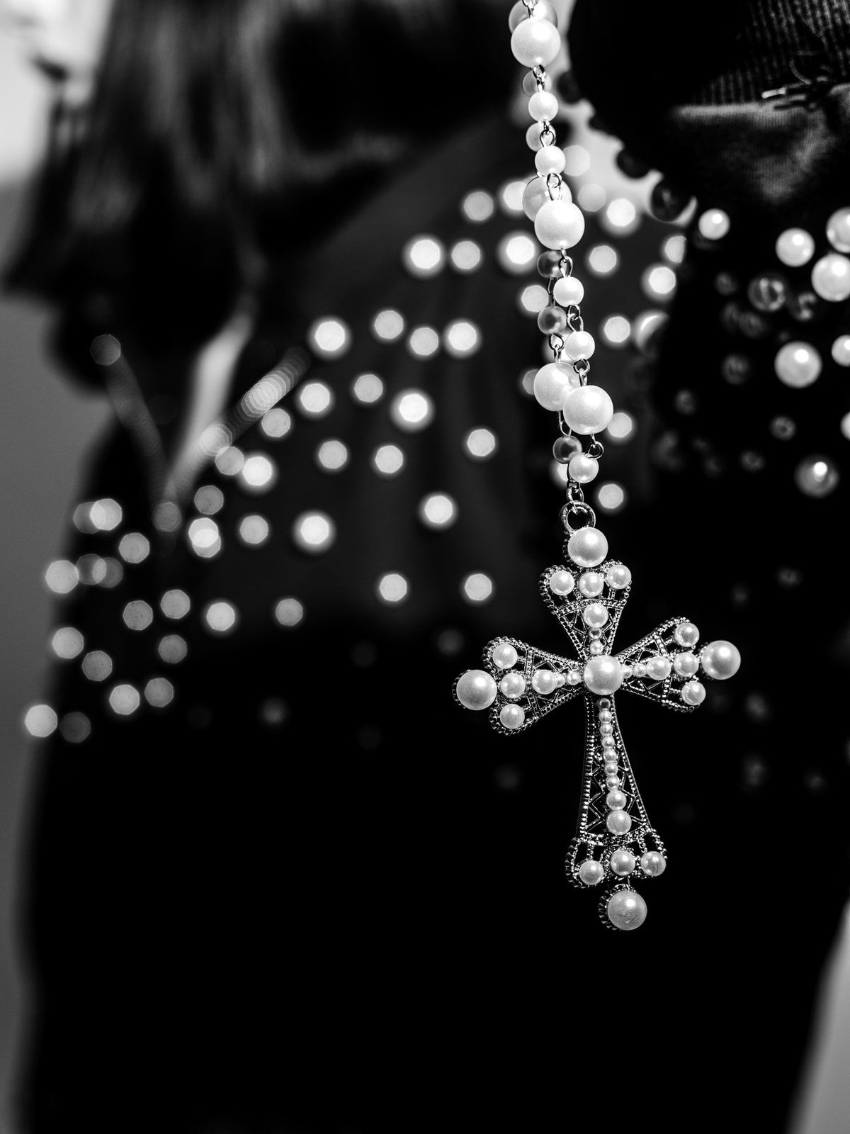 Pearl cross necklace against the pearl shoulder of a zip-up