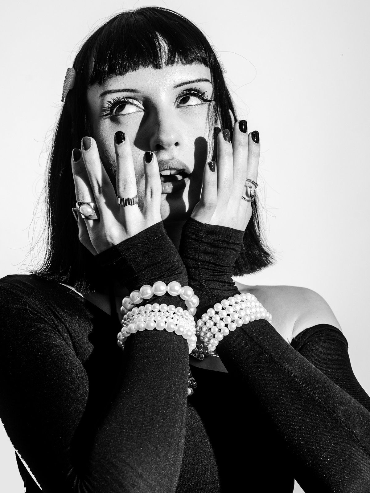 Pearl bracelets stacked on both wrists, hands at the face
